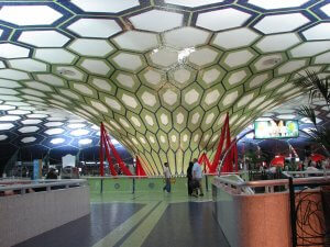 Inside Abu Dhabi International Airport with glass ceiling and people milling around.