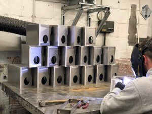 Stacked metal grey boxes and man welding.