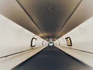 Inside beige-coloured walkway at Gatwick Airport with grey carpet and advertising panels.