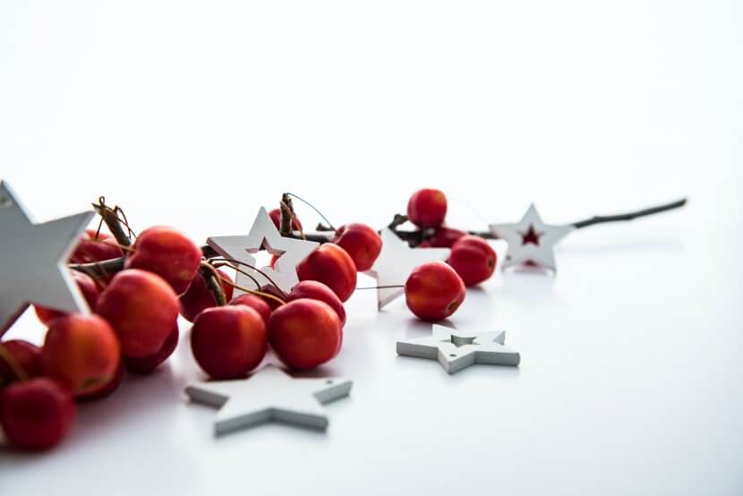Christmas stars and red berries scattered on a table.
