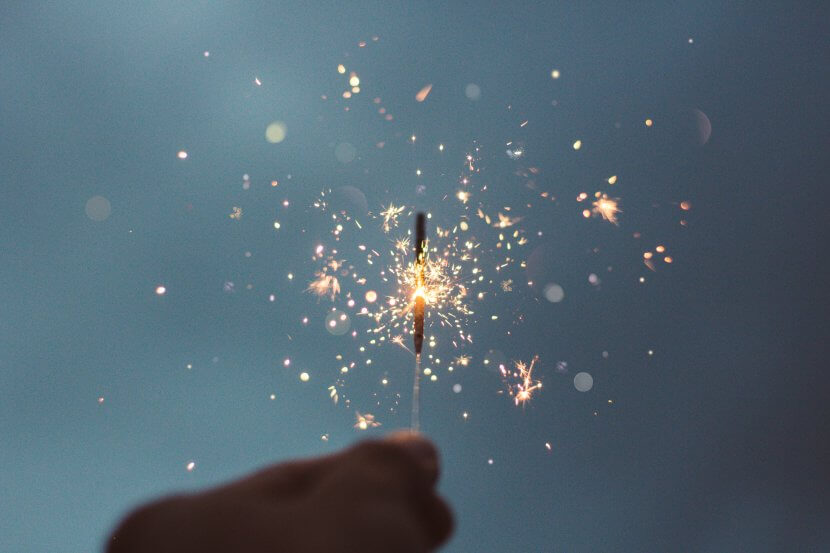 A sparkler held in a hand at night.