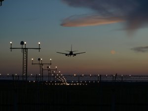 A jumbo jet plane coming in to land at night with runway lights.